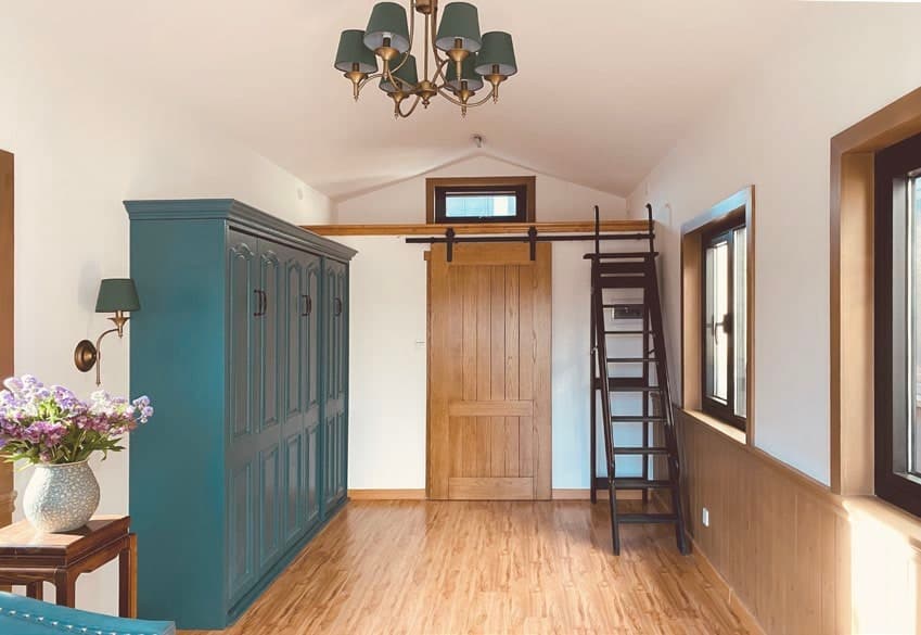 Tiny Villa T1 interior with wood floor, entry door and loft ladder